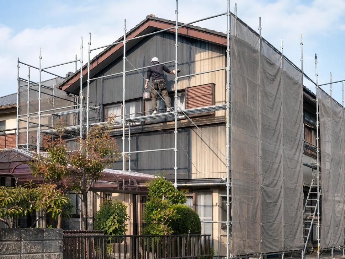 デモ用の生成画像（架空の外壁塗装イメージ）。足場のかかった木造住宅の外壁工事。