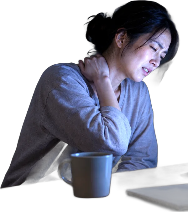 夜、机に向かったまま首の後ろに手を当てる女性