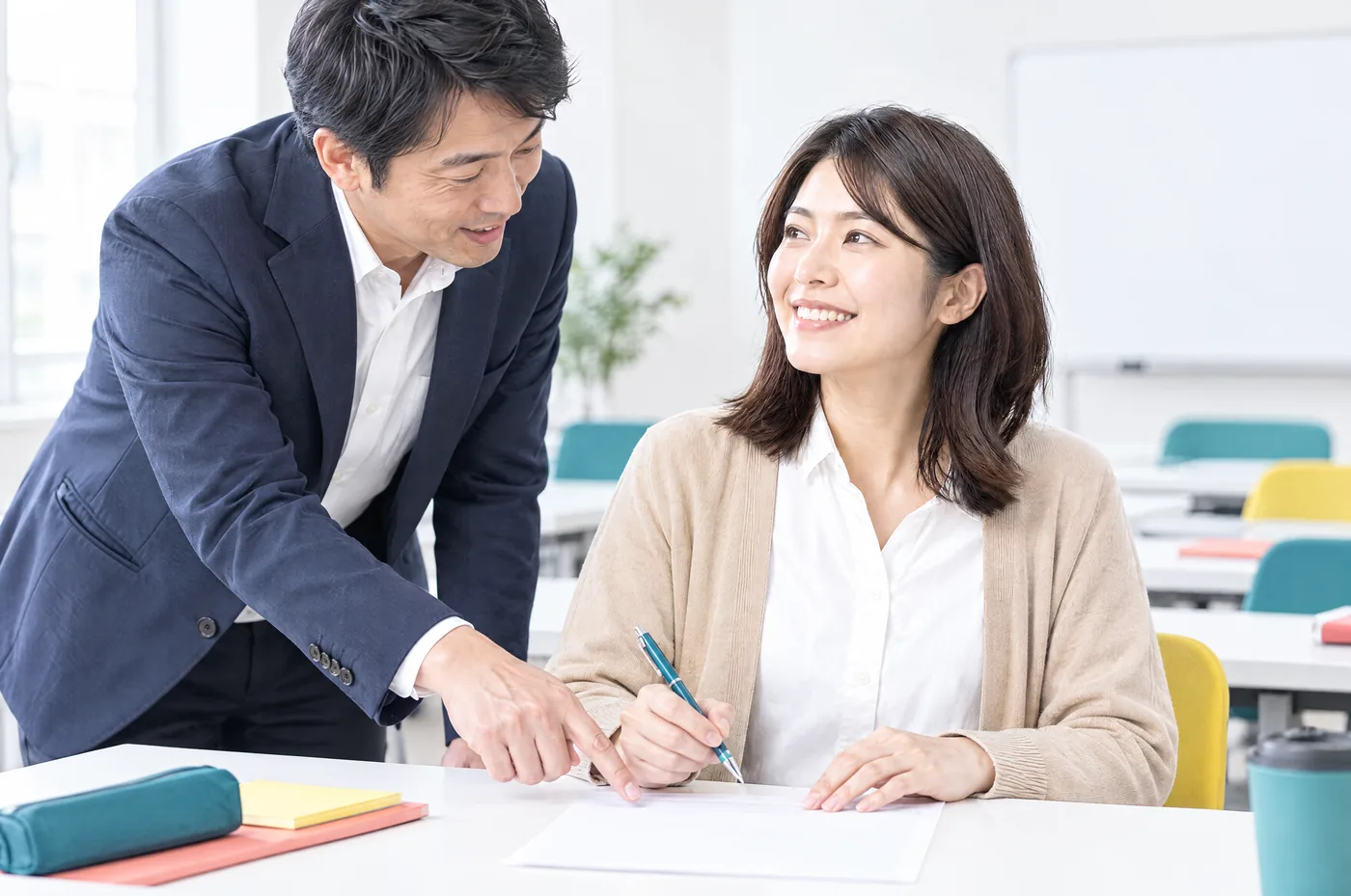 講師が受講者の机のそばに立ち、シートを指して答えている